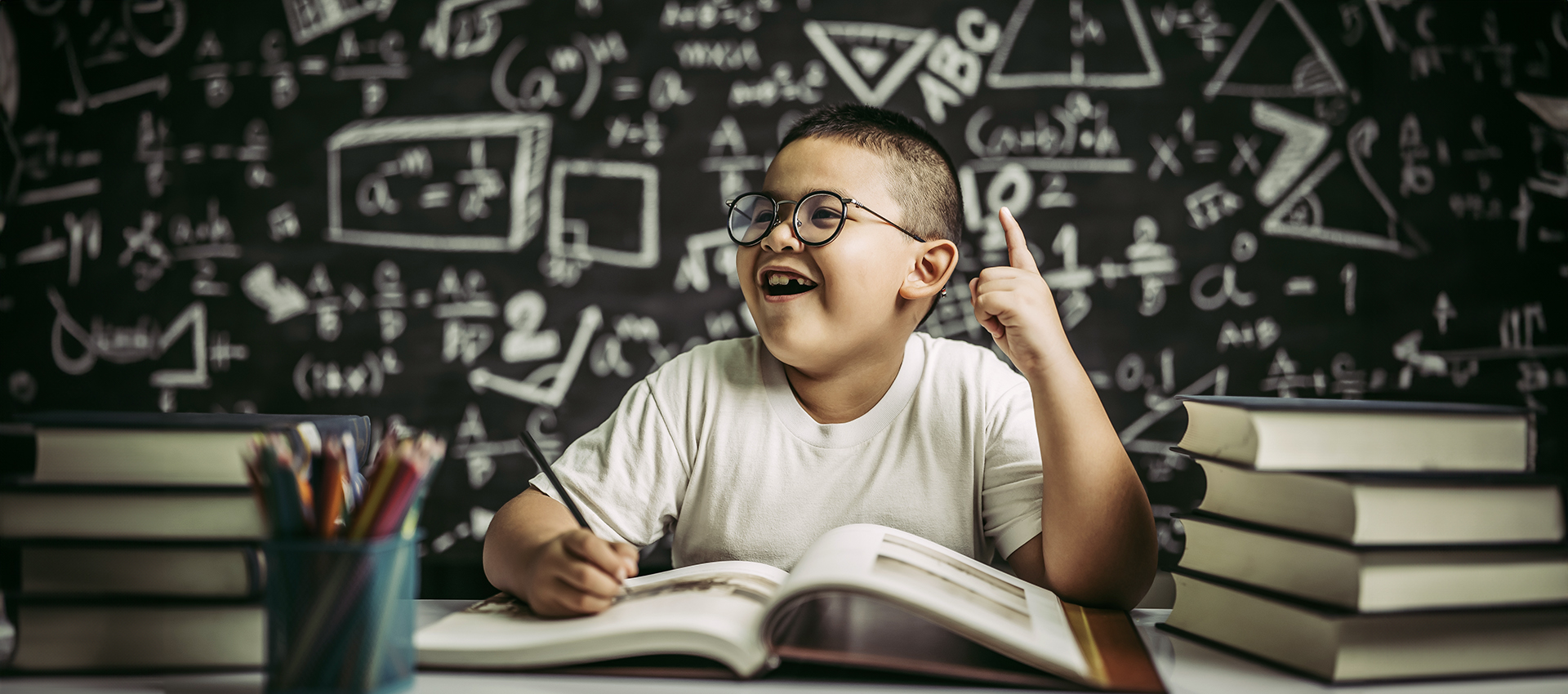 Boys with glasses write books and think in the classroom