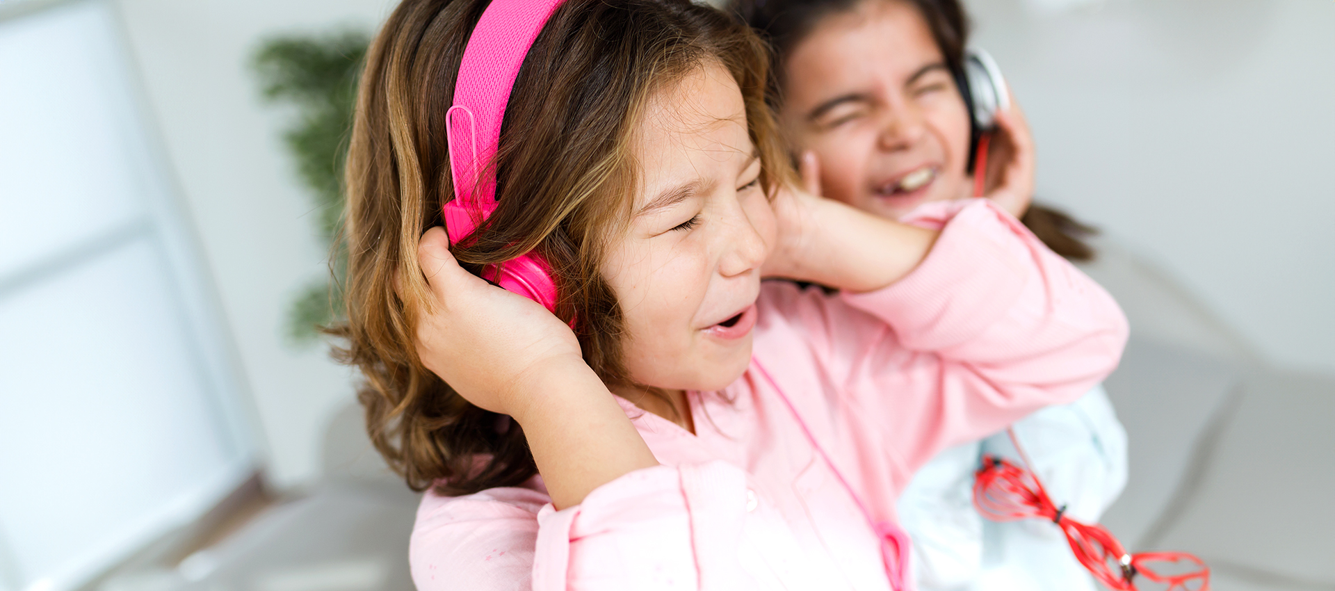 Portrait of two young sisters listening to music and dancing at home.