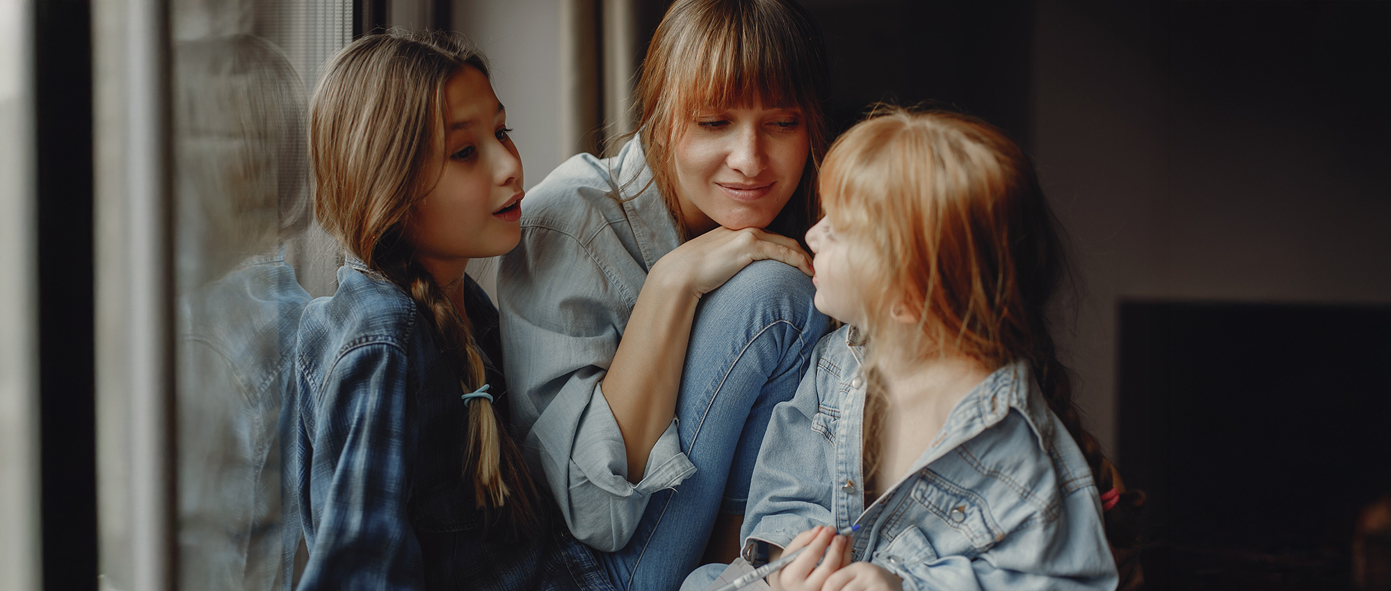 Beautiful mother with two daughters. Family sitting in the room near window
