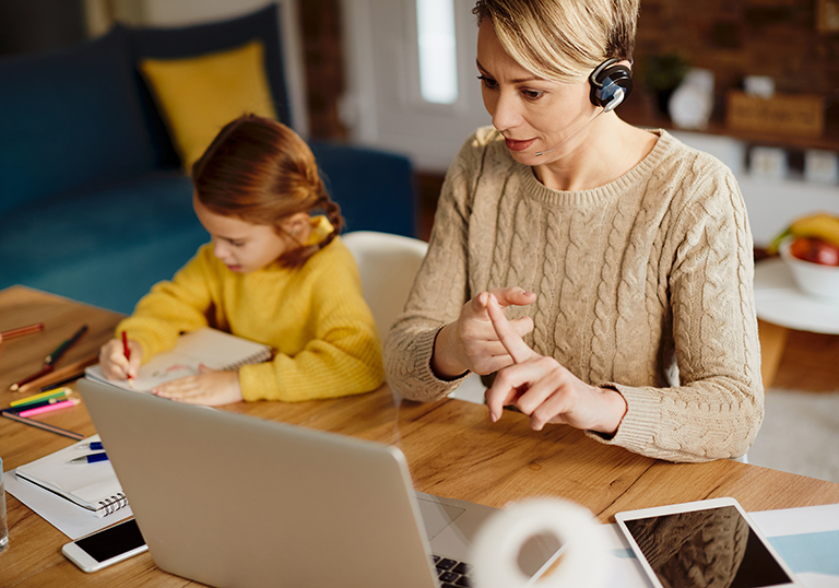 Single mother using computer and making video call while working from home.